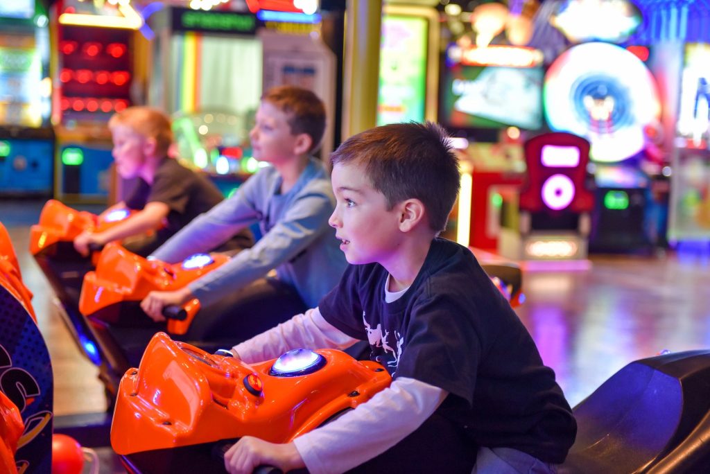 Young boy and his friends playing a motorcycle race arcade game
